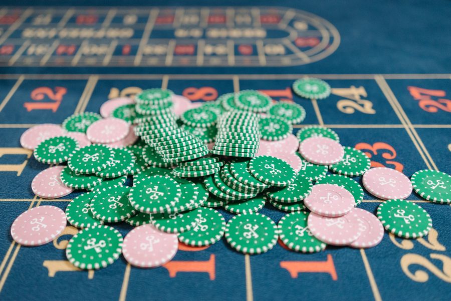 Tumpukan chip kasino hijau dan merah muda di atas meja