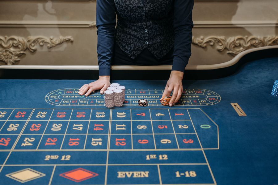 Tangan memegang chip poker kuning di meja kasino